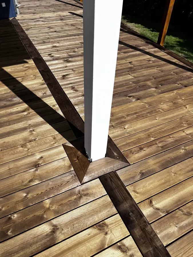 Detalje af terrassebrædder samlet omkring en hvid stolpe